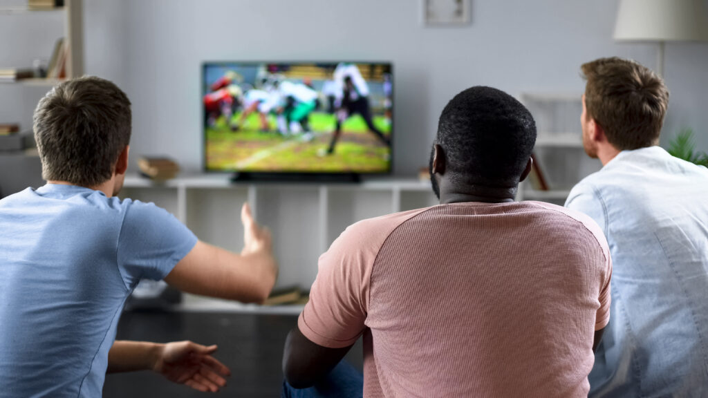 Three men sitting in the living room watching a sports game.