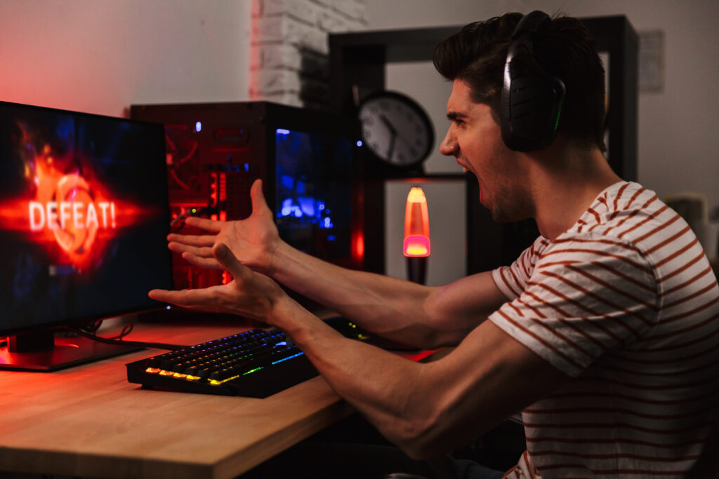 Frustrated man screaming at his computer after being beaten at his online game.