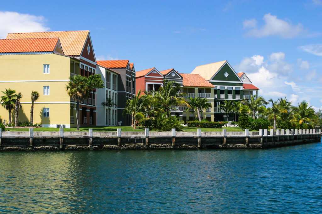 Several multi-unit buildings overlooking the water, surrounded by grass and palm trees.