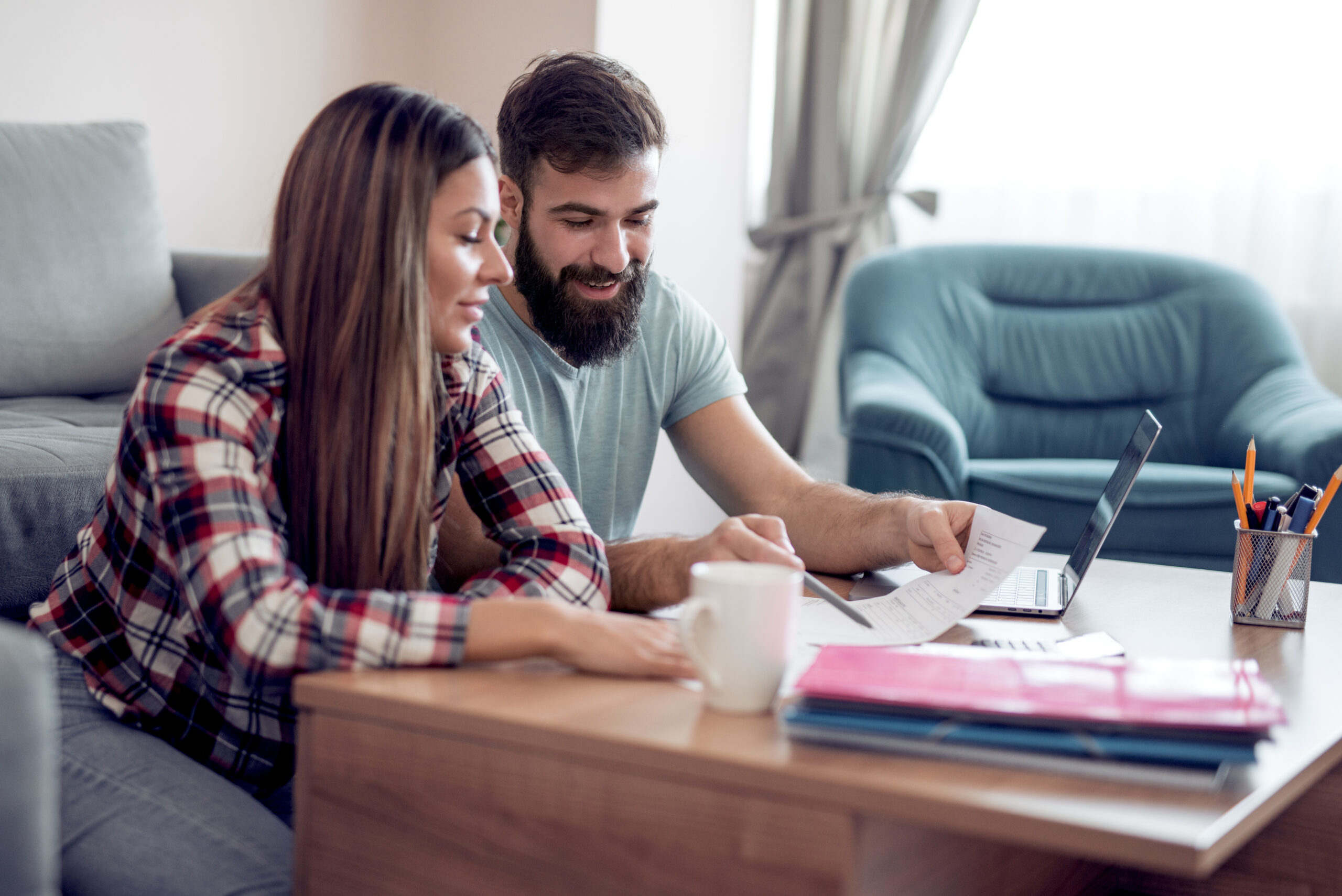 Man and woman sitting on the couch while reviewing their finances together.