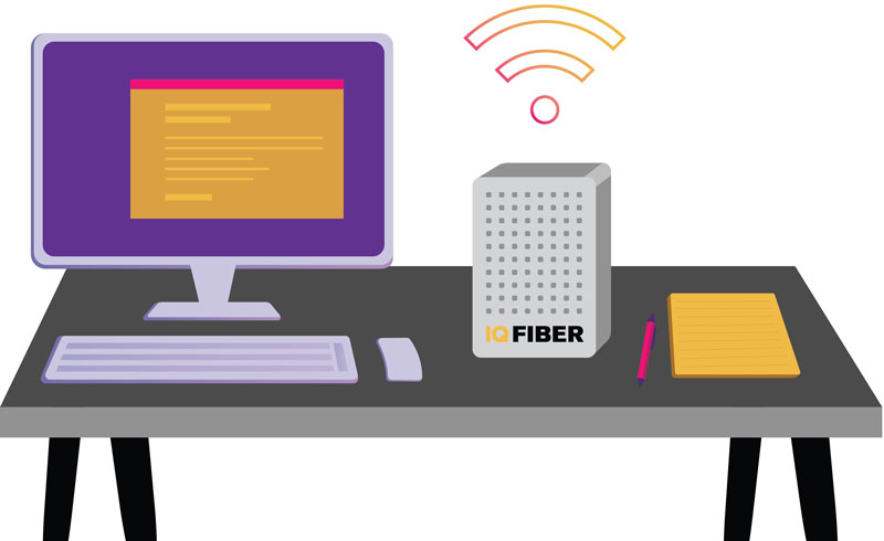 IQ Fiber router on a desk next to a computer and notebook.