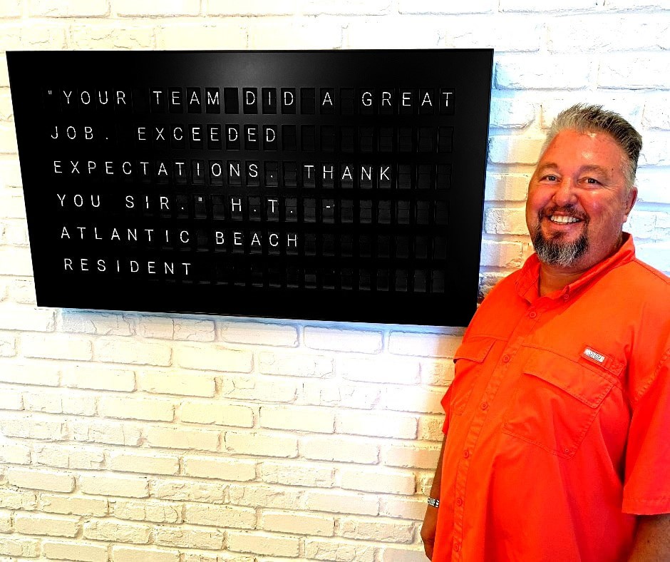 IQ Fiber employee standing in front of Vesta Board showing a happy customer testimonial.