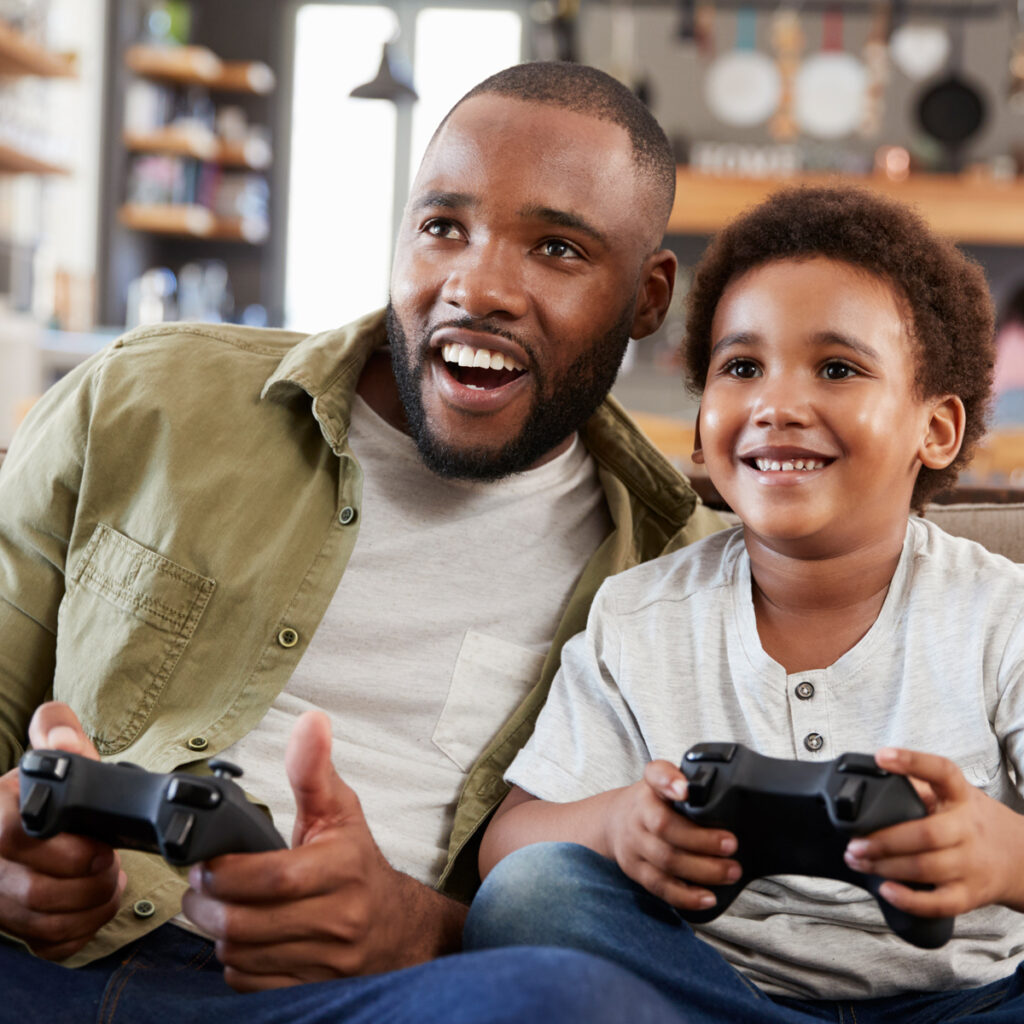 A father and son playing video games together on the couch.